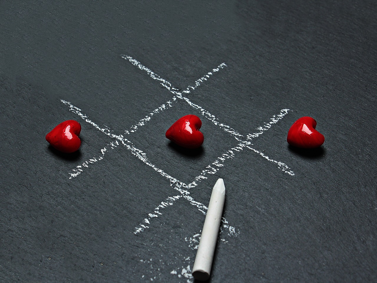 Tic-tac-toe with hearts on a chalkboard.