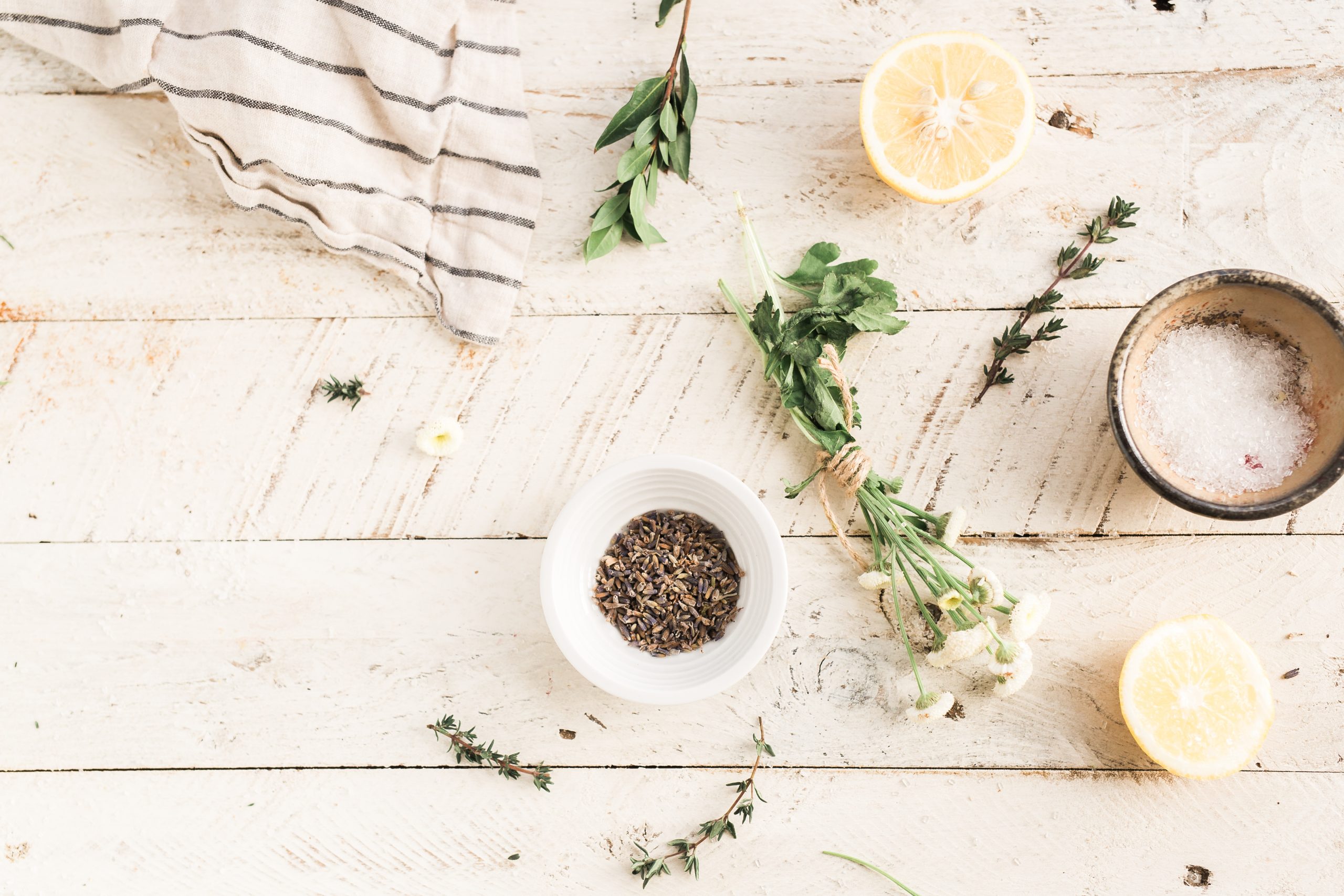 A bowl of herbs and lemons on a wooden table.