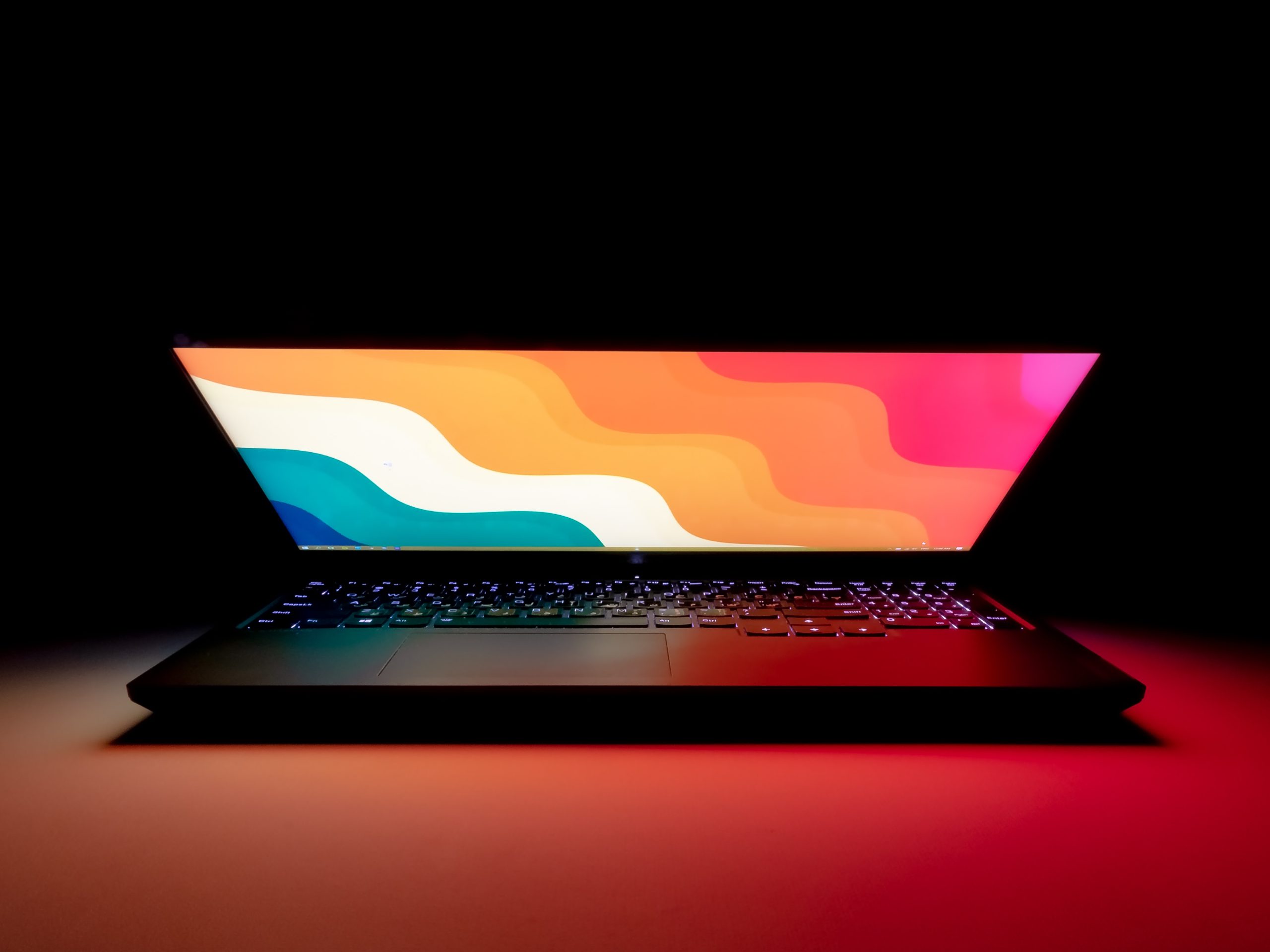 A laptop with a colorful screen on a dark background.